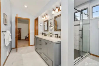 View in the primary bathroom from the walk-in closet, showing the vanity, gorgeous tile floors and the shower.
