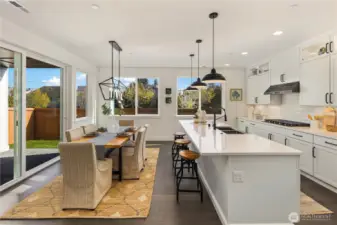 Kitchen & Dining  This connected kitchen and dining space highlights the seamless main-level layout central to modern Pacific Northwest design. A quartz island with bar seating anchors the kitchen, complemented by full-height cabinetry, a gas cooktop, wall oven, and under-cabinet lighting. Expansive windows and a sliding glass door create an easy transition to outdoor living while filling the space with natural light.    Located in Bothell’s Canyon Park neighborhood, this open living area reflects the quality and finish expected in luxury new construction within the Northshore School District.    These photos are from a past Robinson Plan at a different community, so overall plan, colors, building orientation, finishes, home outlook, and other details can and WILL vary. All photos, renderings, site maps, and floorplans are for visualization purposes only.