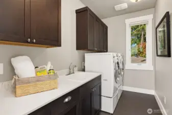 Convenient upper-level laundry with a utility sink and plenty of built-in storage.