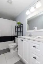 Main bathroom with ceramic tile flooring, custom vanity and granite counters.
