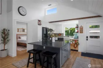 Large kitchen island with quartz countertops & pull out spice and wastebasket cabinets.