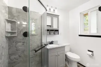 Primary bedroom quarter bathroom shower, vanity and toilet seat with window and storage
