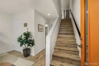 Inviting entryway with warm wood floors and a modern staircase leading to the main living spaces