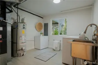 Large laundry room with utility sink, washer and dryer. Gas furnace and gas water heater.