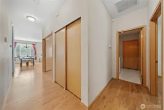View standing at primary bedroom door looking towards the laundry room with garage door access.  A peek of the door frame to bedroom 2 on the right.