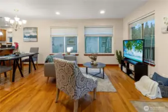 Comfortable living area with hardwood floors, recessed lighting, and large windows that bring in natural light and wooded views. Open layout connects seamlessly to the dining space and kitchen.