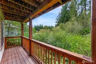 Covered deck off the living room overlooks the backyard and nearby Lake Louise area, offering a peaceful outdoor space to enjoy morning coffee or evening relaxation.