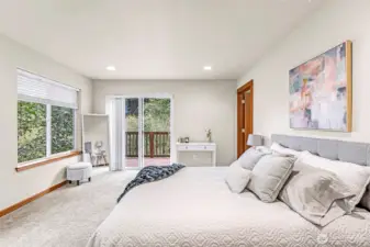 Spacious primary bedroom with soft natural light, neutral finishes, and direct access to the private deck at the back of the home.