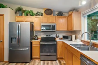 Kitchen with newer ss appliances, fixtures, view to private deck.