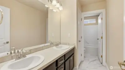 Upstairs guest bathroom with dual sinks and separate toilet/tub/shower area