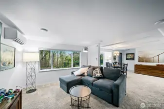 The living room is full of light, with nature views, a cozy gas fireplace, plus ductless heat pump for energy efficient heating and cooling