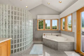 Jetted tub in the primary suite with an abundance of natural lighting, private access to hot tub and pool and sweeping pasture views.