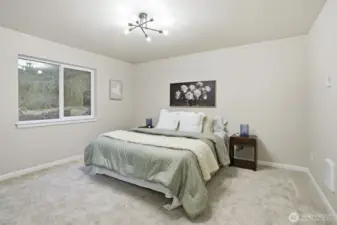 Spacious primary bedroom with large window overlooking the backyard