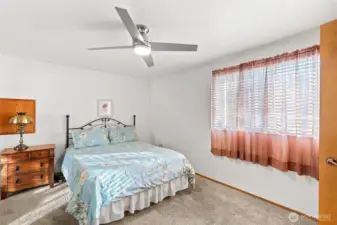 Spacious carpeted bedroom featuring a ceiling fan for year-round comfort.