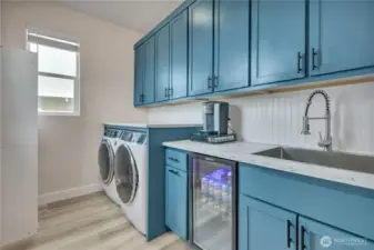 Large upper laundry with ample cabinets and beverage fridge