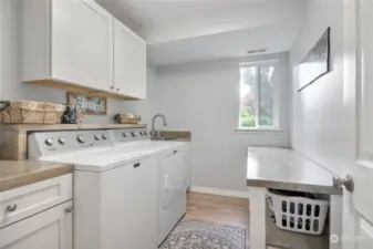 Great laundry room with cabinets, built-in utility sink, folding table & a window to let in natural light