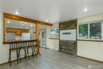 A rustic wood accent wall provides a focal point for mounting a television, while large windows fill the room with natural light and offer views of the backyard.