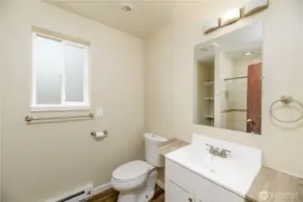 Private en-suite three-quarter bathroom featuring a modern vanity with counter space, updated lighting, and a large mirror.