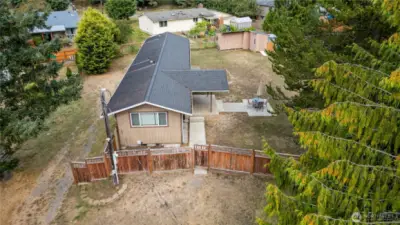 Bird’s-eye view of the back of the home, covered patio, and outdoor entertaining space. The layout emphasizes both privacy and usability, with the home nestled into a generous lot surrounded by trees.