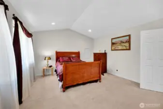 Primary bedroom with high vaulted ceilings and recessed lighting.