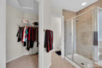 This shows a portion of the walk in closet, walk in tile shower and water closet in the primary bathroom.