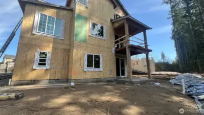 Rear view picture of back of home & yard.  Covered deck going in on main level plus a patio on lower level.