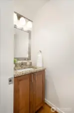 Main-level Powder Bath offers warm wood cabinets for storage.