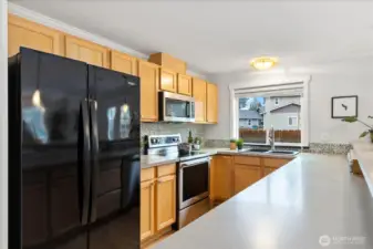 Spacious kitchen with beautiful maple cabinetry, an abundance of counterspace, and newer appliances...dishwasher, range and microwave (1/2025), refrigerator (2019).