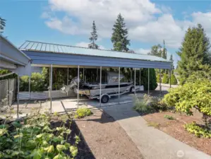 Covered RV or boat parking behind fence.
