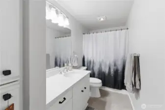 Guest bath with quartz countertops, undermount sink, tub/shower combo and built-in linen storage.