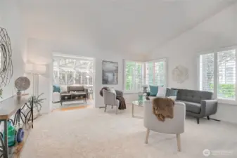 Living room with vaulted ceilings, new paint, carpet. Lots of natural light, shutters, and adjoined by the delightful sunroom.