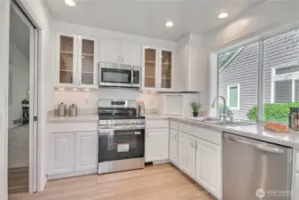 Kitchen features display cabinets, recessed lighting and fresh white cabinets.