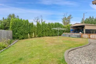 Fenced off back yard for a small dog, raised garden beds, and carport.