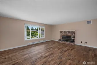 This inviting living room boasts a large picture window that fills the space with natural light and a charming brick fireplace as the perfect focal point for relaxing or entertaining.