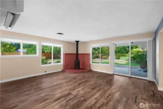 Spacious living room features large windows that flood the space with natural light and a cozy wood stove for added warmth and charm.