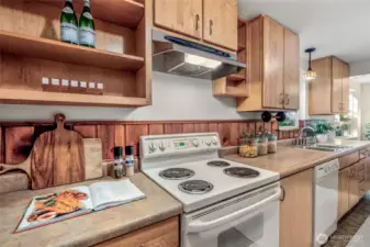 Kitchen has tons of storage, with both open and closed shelving. The wood backsplash and cabinets give it a rustic lodge feeling.