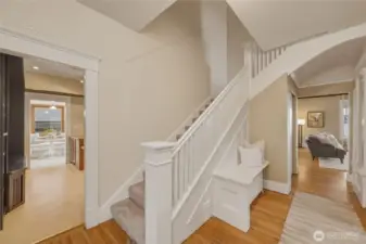 Classic entry foyer featuring original staircase, detailed millwork, and warm hardwood floors.