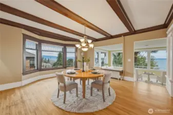 Elegant dining room featuring box-beam ceilings, leaded glass bay windows, and warm hardwood floors.
