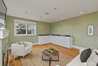 Bright lower-level living area with oak floors and built-in cabinetry—ideal for guests or extended living.  Plumbing available in the wall for future sink install.