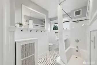 Bright second-floor guest bathroom with subway tile tub surround and pedestal sink
