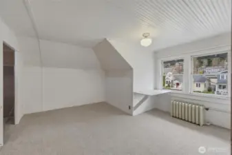 Third-level bedroom with dormer ceilings, built-in desk, and neighborhood outlook