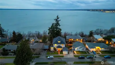 Twilight aerial showcasing the home’s elevated setting and sweeping bay views.