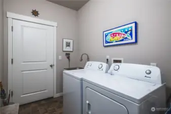 Freshly painted laundry room with white appliances and a handy utility sink.