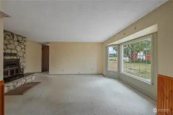 Large family room, with homey wood burning fireplace and large windows.