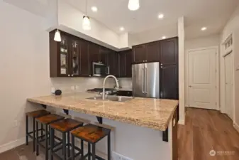 Kitchen bar for seating is very roomy!  Down the hall you can see the transom window over den entrance.  There are bi-fold doors added leading into the den but they can easily be removed if new owner has different needs.