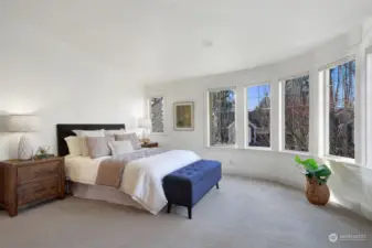 Relaxing primary suite with remote controlled blinds, soaking tub and gas fireplace. Rounded, sheer wall of windows and vaulted ceilings bring in the natural sunlight year-round. This bedroom design is one of a kind.