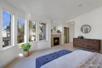 Relaxing primary suite with remote controlled blinds, soaking tub and gas fireplace. Rounded, sheer wall of windows and vaulted ceilings bring in the natural sunlight year-round. This bedroom design is one of a kind.