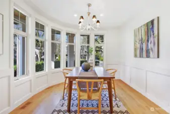 Architecturally interesting, rounded wall of windows is the other side of the charming wrap-around porch. Formal dining room with chandelier and warm oak floors will easily accommodate seating for 6-8.