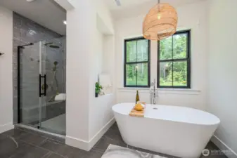 Everything about this space invites rest and relaxation.  Imagine soaking in the gorgeous 67" free-standing tub while enjoying serene backyard views or stepping into the grand walk-in shower with full tile surround, glass enclosure, dual rain shower heads and wands, built-in bench and storage nook. Love the classic tile flooring and pretty wicker light fixture. Private water closet to the right and walk-in closet to the left.