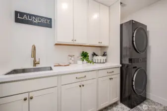 Laundry day just got an upgrade-- with quartz counters, ample storage in soft close cabinetry, a deep, stainless steel utility sink and stunning designer tile underfoot. This space blends elegance with everyday ease.